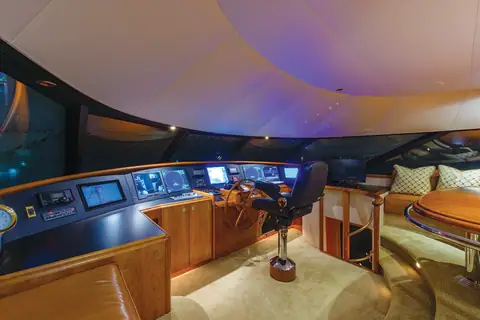 Westport 112 pilothouse with helm chair, wide console of displays and a settee behind