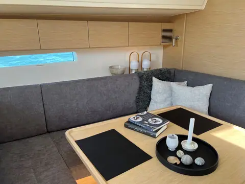 X Yachts X4.3 saloon with gray U shaped settee, oak table and hull windows