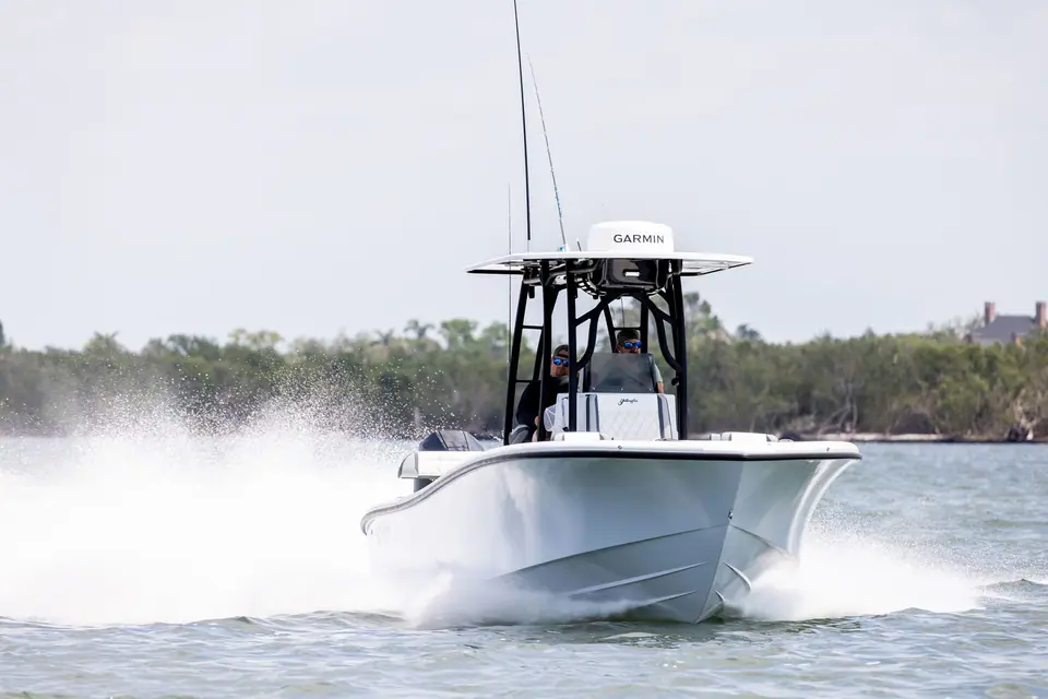 Yellowfin 26 Hybrid running toward the camera across a shallow bay with its T top and antennas