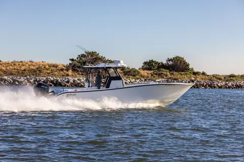 Yellowfin 32 Offshore running past a rock jetty with its T top and outriggers