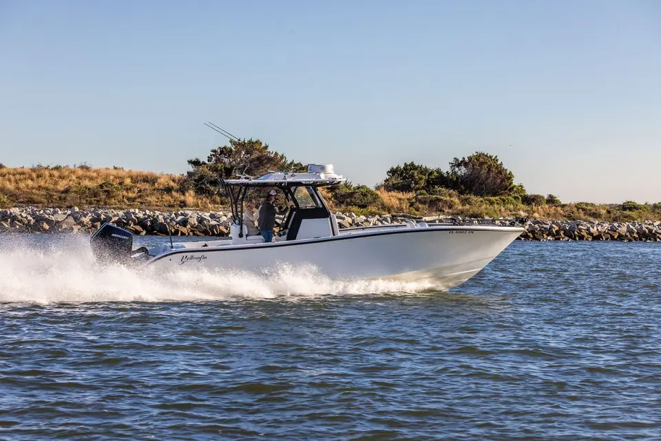 Yellowfin 32 Offshore running past a rock jetty with its T top and outriggers