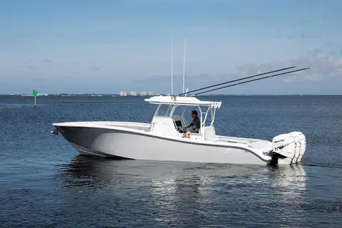 Yellowfin 34 Offshore with triple outboards idling on calm water near the coast