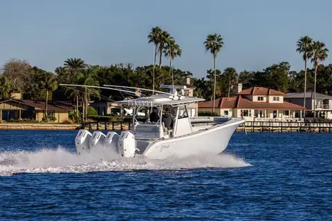 Yellowfin 39 Offshore with quad white outboards running past palm lined waterfront homes