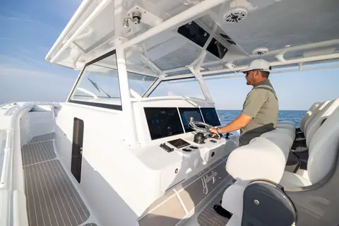 Captain at the Yellowfin 54 Offshore helm behind the windshield with large displays